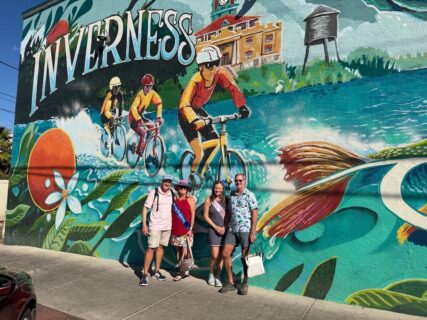 Couples enjoy Inverness Food Tour in front of the City's mural